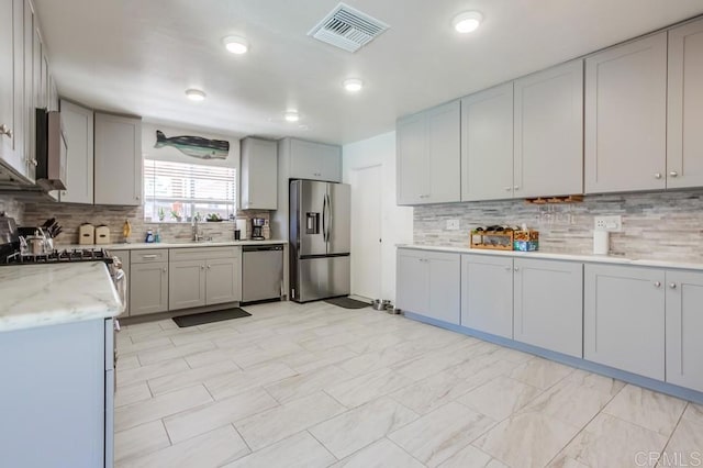 3018 Thunder Dr, Oceanside, CA 92056 - kitchen with appliances with stainless steel finishes, decorative backsplash, gray cabinetry, and light stone countertops