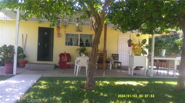 1033 Chapel Dr, Bakersfield, CA 93304 - property entrance with stucco siding, a patio area, and a lawn