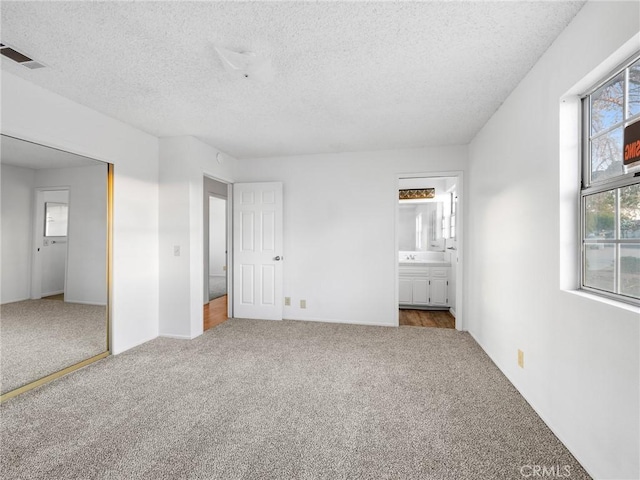 9383 11th Ave, Hesperia, CA 92345 - unfurnished bedroom featuring carpet floors, a textured ceiling, and ensuite bath