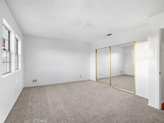 9383 11th Ave, Hesperia, CA 92345 - unfurnished bedroom featuring a textured ceiling, carpet, and a closet