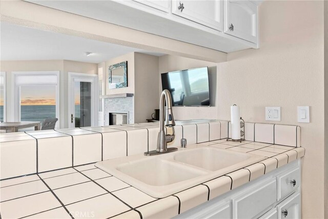 9229 Balboa Ave Unit 4, San Simeon, CA 93452 - kitchen view of tile counters, white cabinetry, and a stone fireplace
