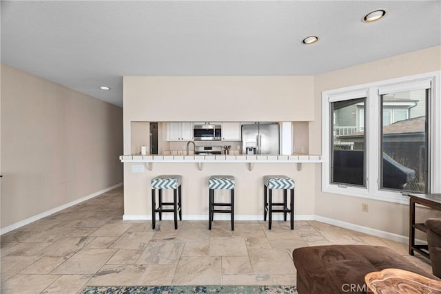 9229 Balboa Ave Unit 4, San Simeon, CA 93452 - kitchen with stainless steel appliances, a kitchen bar, light stone finish flooring, a peninsula, and recessed lighting