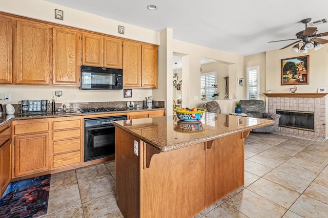11337 Vista Elevada, San Diego, CA 92131 - kitchen with black appliances, a center island, dark stone countertops, a tiled fireplace, and a breakfast bar area