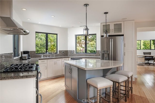 125 Park Pl, Pismo Beach, CA 93449 - kitchen featuring island exhaust hood, healthy amount of natural light, dark stone countertops, a kitchen bar, and recessed lighting