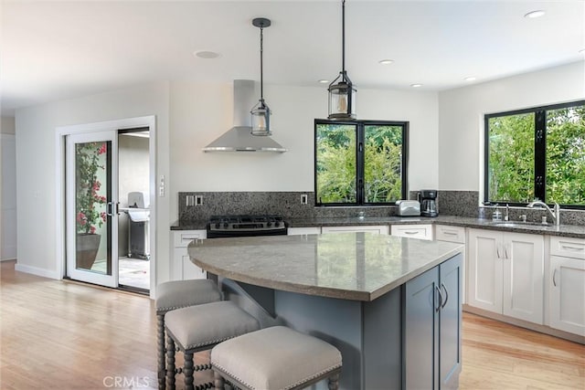 125 Park Pl, Pismo Beach, CA 93449 - kitchen with wall chimney range hood, dark stone countertops, light wood-type flooring, white cabinets, and recessed lighting