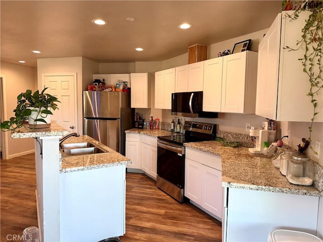 2048 10th St, Oroville, CA 95965 - kitchen featuring appliances with stainless steel finishes, recessed lighting, white cabinets, dark wood-style flooring, and a center island with sink