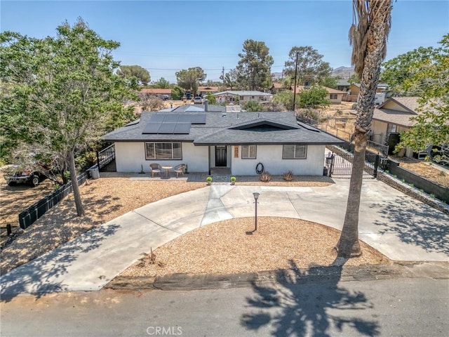 7573 Cibola Trl, Yucca Valley, CA 92284 - single story home with solar panels, concrete driveway, roof with shingles, and stucco siding