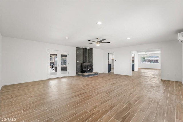 7573 Cibola Trl, Yucca Valley, CA 92284 - unfurnished living room with a wood stove, light wood-style flooring, ceiling fan, recessed lighting, and french doors