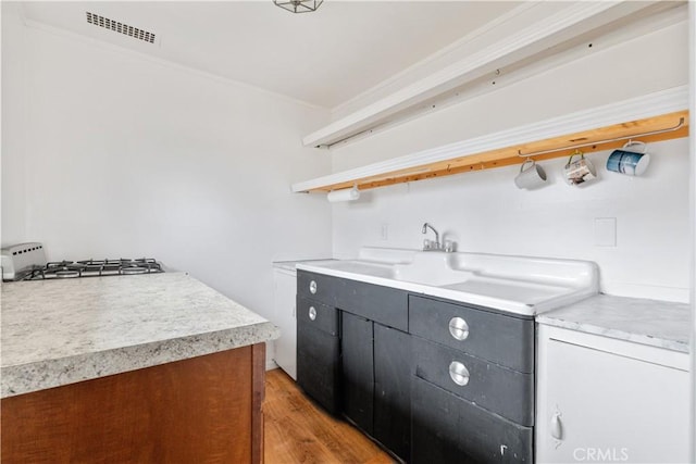 971 Ramona Ave, Los Osos, CA 93402 - kitchen with light countertops, light wood-style floors, open shelves, stainless steel gas stovetop, and dark cabinets