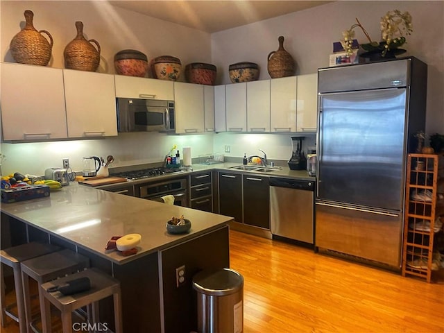 801 S Grand Ave Unit 1608, Los Angeles, CA 90017 - kitchen with stainless steel appliances, light wood-type flooring, a peninsula, a breakfast bar, and white cabinetry