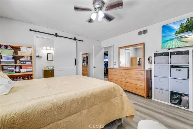 5622 Sharon Way, Jurupa Valley, CA 92509 - bedroom with light wood-style flooring, a barn door, connected bathroom, a ceiling fan, and a spacious closet