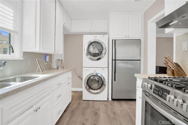 3341 Wisconsin Ave, South Gate, CA 90280 - kitchen with stainless steel appliances, exhaust hood, stacked washer / drying machine, light wood-type flooring, and white cabinets