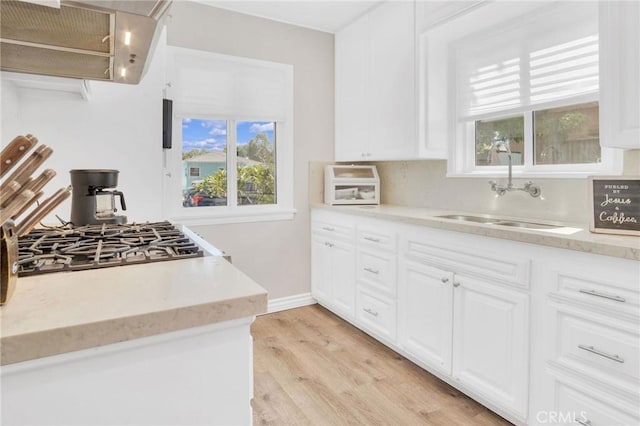 3341 Wisconsin Ave, South Gate, CA 90280 - kitchen featuring exhaust hood, light wood finished floors, white cabinetry, and light stone counters