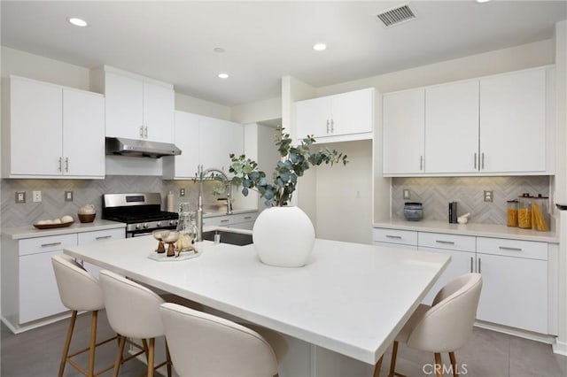 26 Prominence, Lake Forest, CA 92630 - kitchen featuring stainless steel range with gas cooktop, under cabinet range hood, a kitchen bar, backsplash, and recessed lighting