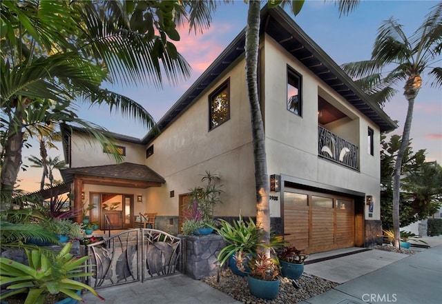 3908 Channel Pl, Newport Beach, CA 92663 - view of front of house with stucco siding, a balcony, a garage, stone siding, and driveway