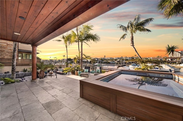 3908 Channel Pl, Newport Beach, CA 92663 - patio terrace at dusk featuring a patio, a jacuzzi, and a water view