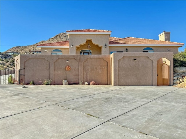 57466 Buena Suerte Rd, Yucca Valley, CA 92284 - view of front facade featuring stucco siding, a tiled roof, a gate, and a chimney