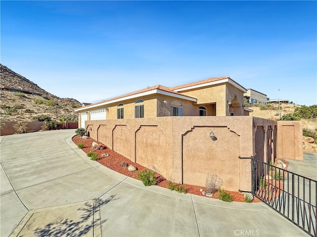 57466 Buena Suerte Rd, Yucca Valley, CA 92284 - view of side of home featuring stucco siding, driveway, a gate, and a tile roof