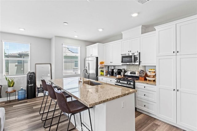7020 Turin Pl, Eastvale, CA 92880 - kitchen with stainless steel appliances, a center island with sink, plenty of natural light, a breakfast bar, and recessed lighting