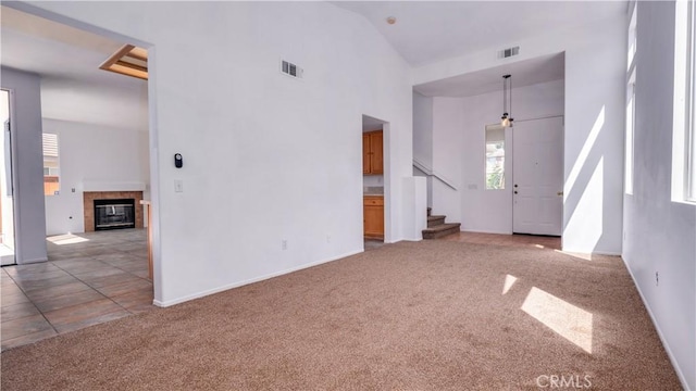 31995 Calle Ballentine, Temecula, CA 92592 - unfurnished living room featuring carpet flooring, plenty of natural light, stairs, a high ceiling, and a tile fireplace