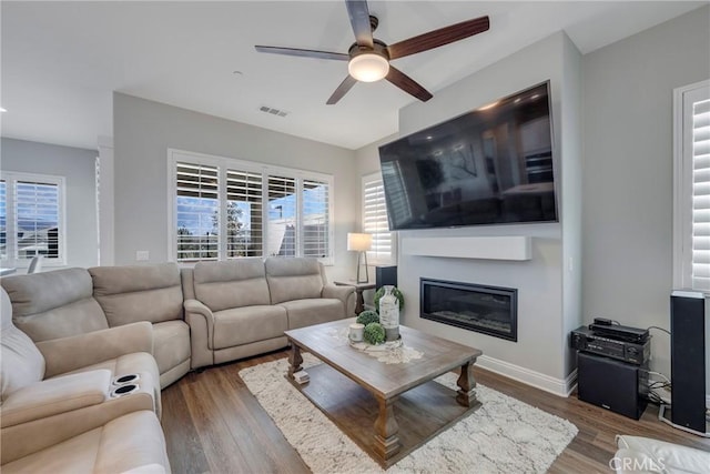 24185 Sprout Dr, Corona, CA 92883 - living area with a ceiling fan, a glass covered fireplace, healthy amount of natural light, and wood finished floors