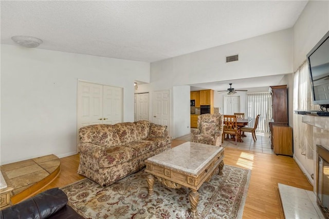 736 Highland Pl, San Dimas, CA 91773 - living area featuring a ceiling fan, light wood-type flooring, a tile fireplace, lofted ceiling, and a textured ceiling