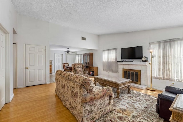 736 Highland Pl, San Dimas, CA 91773 - living area featuring a textured ceiling, a tile fireplace, light wood-style flooring, and a ceiling fan