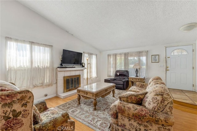 736 Highland Pl, San Dimas, CA 91773 - living room featuring a textured ceiling, healthy amount of natural light, a tiled fireplace, wood finished floors, and vaulted ceiling