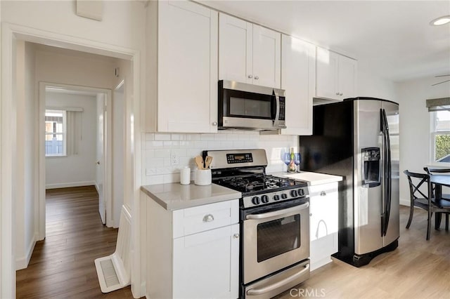 4709 W 149th St, Lawndale, CA 90260 - kitchen featuring appliances with stainless steel finishes, decorative backsplash, light countertops, light wood-type flooring, and white cabinets