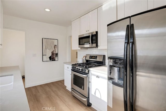 4709 W 149th St, Lawndale, CA 90260 - kitchen featuring appliances with stainless steel finishes, light countertops, light wood finished floors, white cabinetry, and backsplash