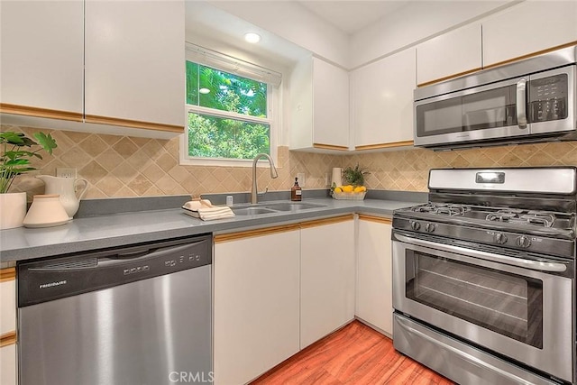 360 S Los Robles Ave Unit 10, Pasadena, CA 91101 - kitchen featuring appliances with stainless steel finishes, light wood-style flooring, white cabinetry, decorative backsplash, and dark countertops