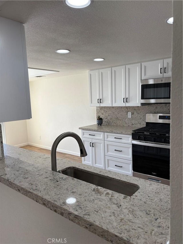 11496 Nautical Ln Unit 19, Helendale, CA 92342 - kitchen featuring appliances with stainless steel finishes, white cabinetry, light stone countertops, a textured ceiling, and recessed lighting