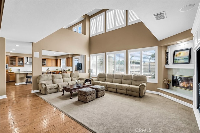 17032 Mountain Crest Ct, Riverside, CA 92503 - living area with a glass covered fireplace, light wood-type flooring, a towering ceiling, and recessed lighting