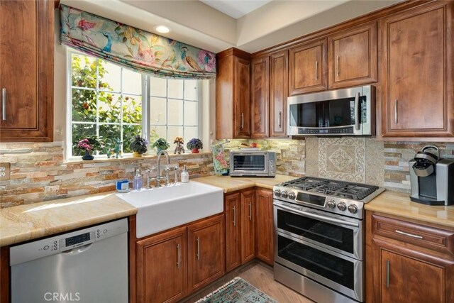 530 Bluerock Dr, San Luis Obispo, CA 93401 - kitchen with appliances with stainless steel finishes, light countertops, brown cabinetry, tasteful backsplash, and light wood-style flooring