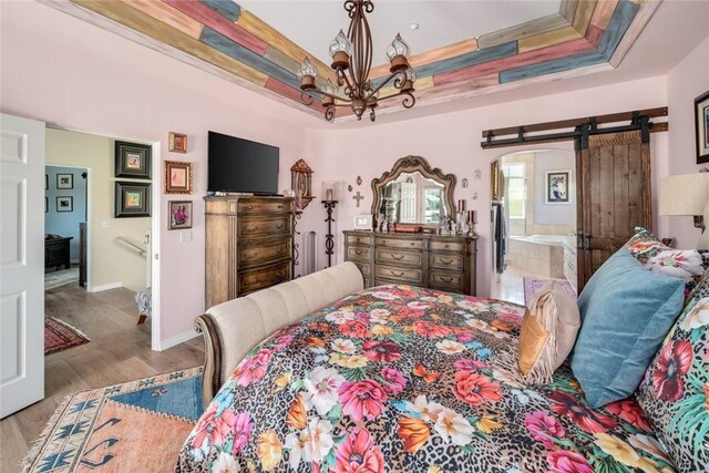 530 Bluerock Dr, San Luis Obispo, CA 93401 - bedroom featuring a raised ceiling, a chandelier, a barn door, wood finished floors, and arched walkways