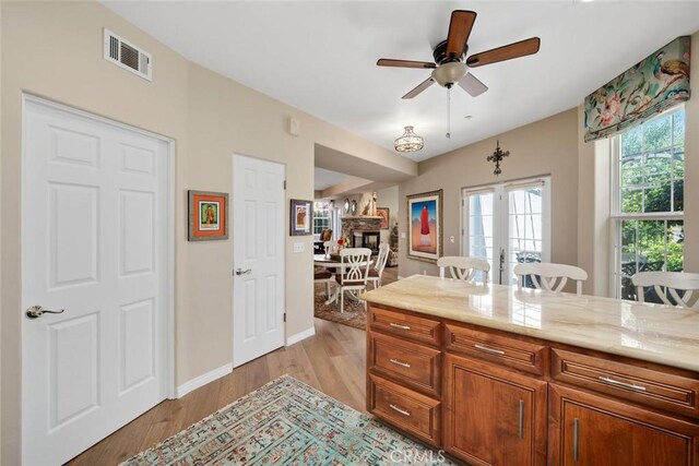 530 Bluerock Dr, San Luis Obispo, CA 93401 - kitchen with light wood finished floors, ceiling fan, a stone fireplace, brown cabinets, and a breakfast bar