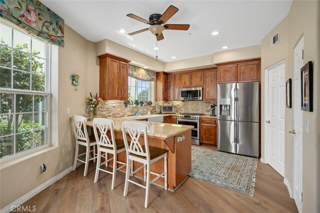 530 Bluerock Dr, San Luis Obispo, CA 93401 - kitchen featuring appliances with stainless steel finishes, a peninsula, brown cabinets, tasteful backsplash, and recessed lighting