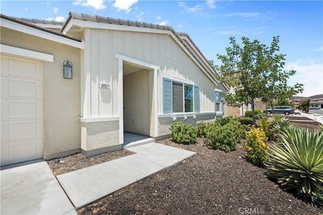 30071 Merrick Ln, Menifee, CA 92584 - property entrance with board and batten siding, a garage, and a tile roof
