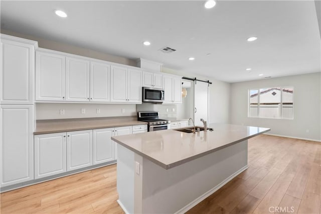 30071 Merrick Ln, Menifee, CA 92584 - kitchen featuring stainless steel appliances, white cabinetry, light wood-style floors, an island with sink, and recessed lighting