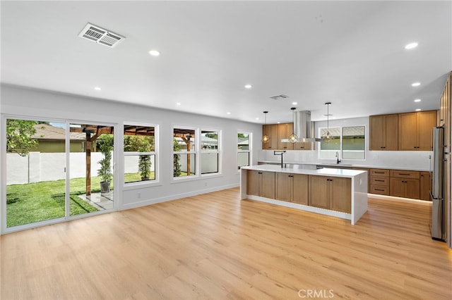 2405 Larchmont Ave, Santa Ana, CA 92706 - kitchen featuring wall chimney range hood, freestanding refrigerator, light countertops, recessed lighting, and light wood finished floors