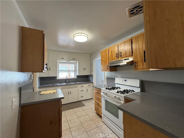 714 E Chapman Ave, Fullerton, CA 92831 - kitchen with white gas stove, under cabinet range hood, light tile patterned floors, and dark countertops