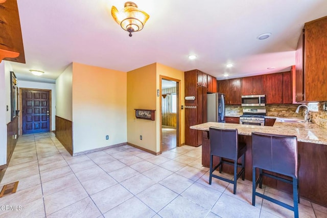 352 Cedarbrook Dr, Twin Peaks, CA 92391 - kitchen with appliances with stainless steel finishes, light stone countertops, a peninsula, light tile patterned flooring, and backsplash