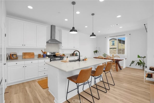 389 Allen Dr, Santa Paula, CA 93060 - kitchen featuring wall chimney range hood, stainless steel gas stove, light wood-style flooring, white cabinets, and recessed lighting