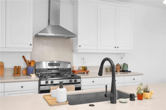 389 Allen Dr, Santa Paula, CA 93060 - kitchen featuring wall chimney range hood, stainless steel range with gas stovetop, white cabinetry, and light countertops