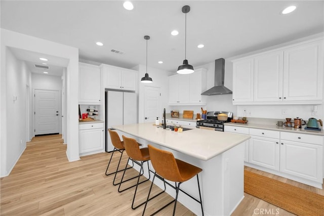 389 Allen Dr, Santa Paula, CA 93060 - kitchen with wall chimney exhaust hood, stainless steel gas stove, freestanding refrigerator, white cabinets, and recessed lighting