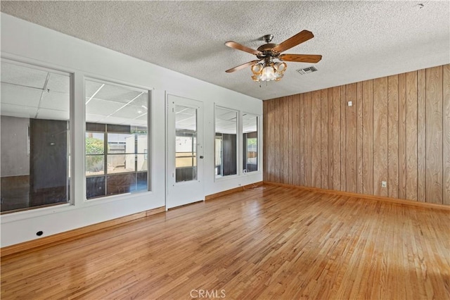 7737 Nestle Ave, Reseda, CA 91335 - unfurnished room featuring hardwood / wood-style floors, wood walls, ceiling fan, and a textured ceiling