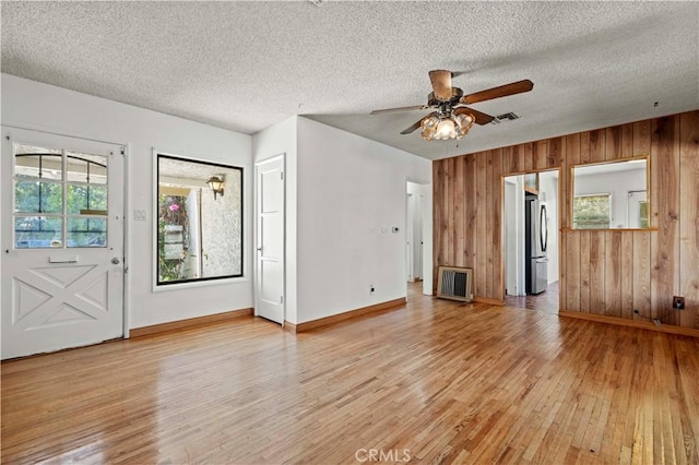 7737 Nestle Ave, Reseda, CA 91335 - unfurnished living room with light wood-style flooring, a ceiling fan, wooden walls, and a textured ceiling