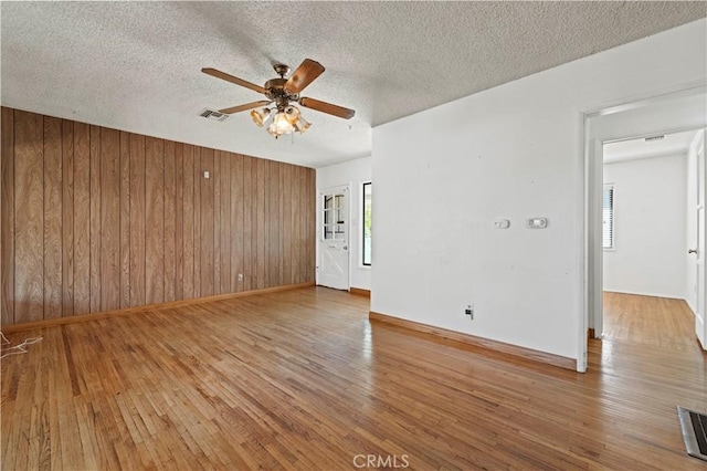 7737 Nestle Ave, Reseda, CA 91335 - empty room with a ceiling fan, light wood-style flooring, wood walls, and a textured ceiling