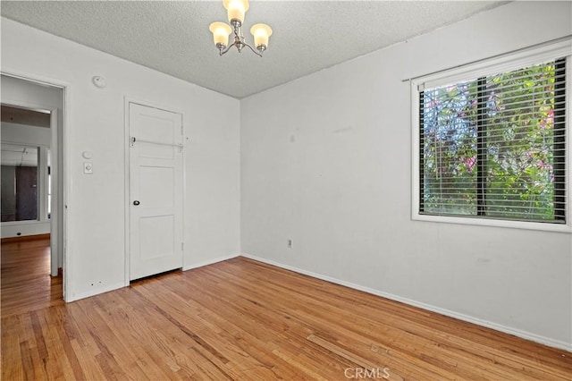 7737 Nestle Ave, Reseda, CA 91335 - empty room with a chandelier, light wood-type flooring, and a textured ceiling