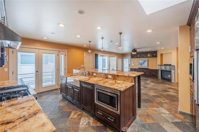 805 Ocean Ave Unit 6, Seal Beach, CA 90740 - kitchen featuring stainless steel microwave, stone tile floors, a glass covered fireplace, dark brown cabinets, and recessed lighting